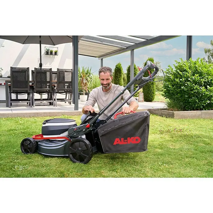 AL-KO 18V/36V Akku-Rasenmäher 51.6 - 18 V - 36 V, 2 Akkus, 8 Ah, Schnittbreite: 51 cm - Ein Mann montiert einen AL-KO Rasenmäher mit Fangkorb in seinem Garten, während er sich auf das Rasenmähen vorbereitet.