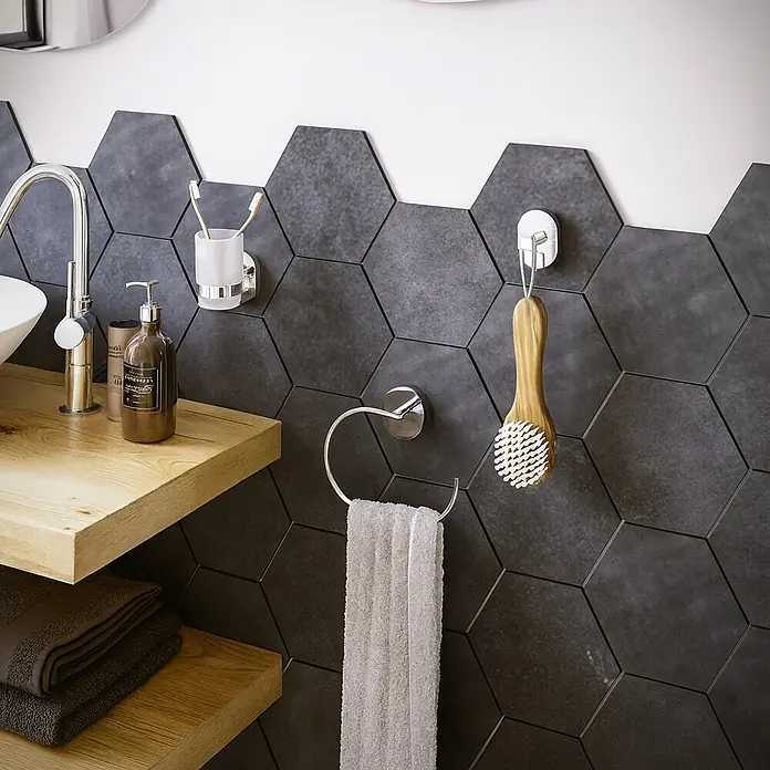 Aquasanit Link Toallero de barra - Ancho: 45 cm - Primer plano de un baño con azulejos hexagonales grises, una mesa de madera y accesorios plateados.