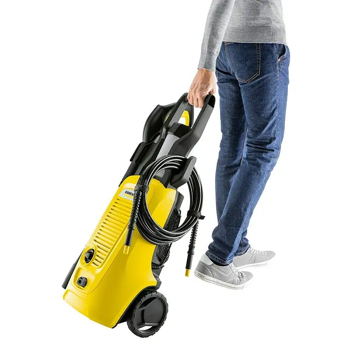 Kärcher Hochdruckreiniger K 4 Universal Edition - 110 bar, 1.800 W, Fördermenge: 420 l/h - Abbildung einer gelben Kärcher Hochdruckreinigers mit einer Person, die ihn hält. Ideal für Haus- und Gartenreinigungsarbeiten mit Benutzerfreundlichkeit.
