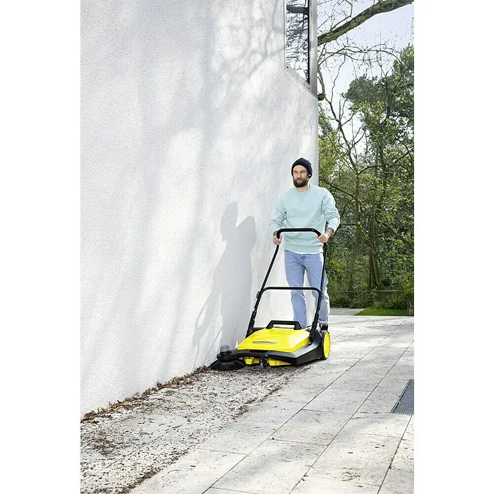 Kärcher Handkehrmaschine S 6 - Flächenleistung: 2.500 m²/h, 38 l - Mann benutzt eine Kärcher Kehrmaschine im Freien, um Blätter und Schmutz zu beseitigen. Ideal für die Reinigung von Gehwegen und Einfahrten.