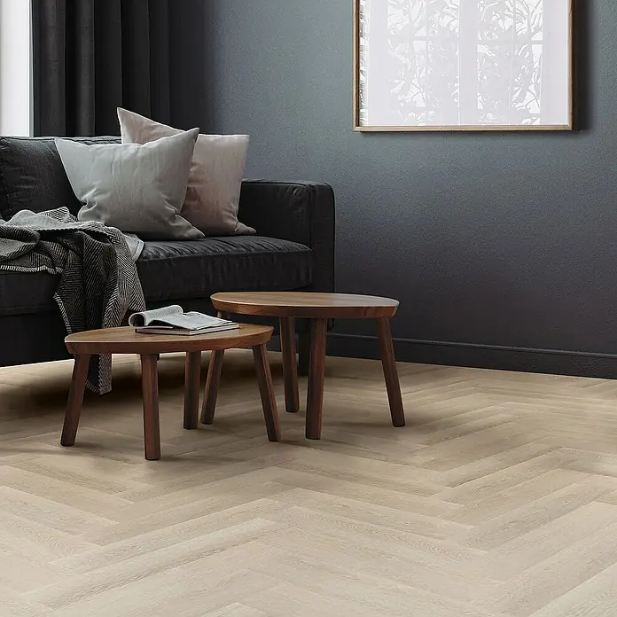ML-Design Vinylboden 4 x Paket Vinylboden mit 80 Diele = 6,2464 m² - Hellbraun, Landhausdiele, 61 cm x 12,8 cm x 4,2 mm - Elegantes Wohnzimmer mit zwei runden Holztischen im Vordergrund, einem dunklen Sofa und einem hellen Fischgrätparkett.