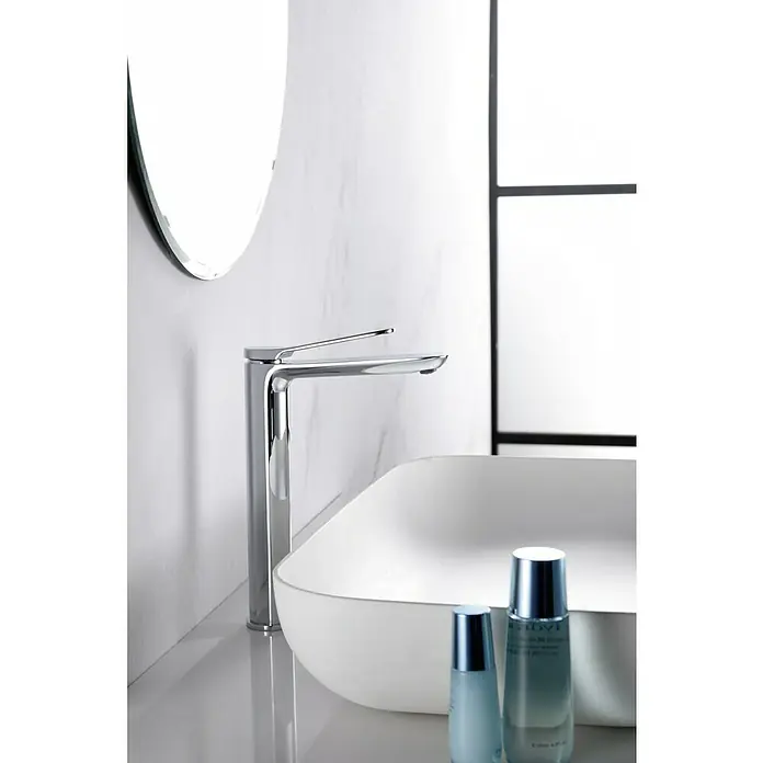 Imex Dinamarca Grifo de lavabo alto - Cromo - Un moderno grifo de baño cromado se encuentra junto a un lavabo con dos productos para el cuidado de la piel, destacando el elegante accesorio.