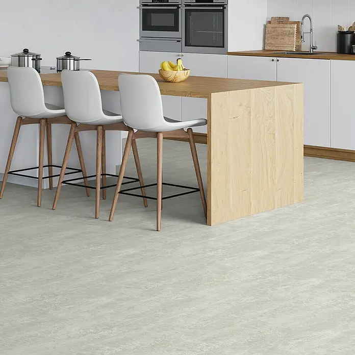b!design Vinylboden SPC - Hellas, Fliese, 609,6 x 304,8 x 3,8 mm - Kücheninterieur mit hellem Bodenbelag, drei weißen Barhockern an einer Holzkücheninsel und Einbaugeräten im Hintergrund.