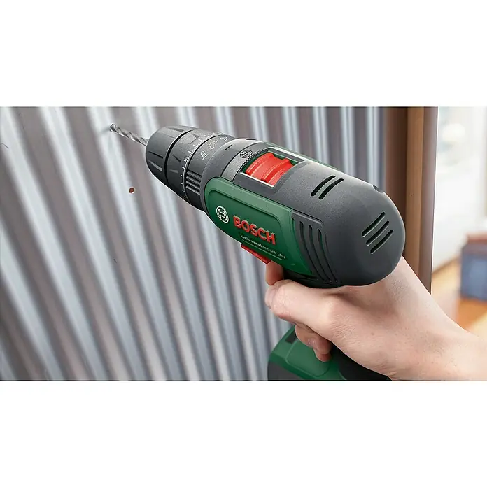 Bosch Power for All 18V Akkuschrauber UniversalImpact 18V - 18 V, 2 Akkus, 1,5 Ah, 241 -tlg. - Ein grüner und grauer Bosch Akku-Bohrer bohrt ein Loch in ein gewelltes Metallstück. Der Bohrer ist mit einem Bohrer versehen.