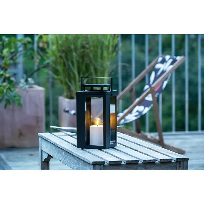 LED-Laterne Lucido - 15 x 15 x 31 cm, Schwarz - Eine moderne schwarze Laterne mit einer strahlenden Kerze auf einem Holztisch, die eine gemütliche Atmosphäre im Freien schafft.