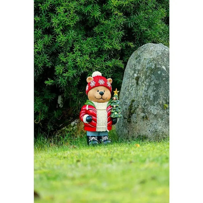 Konstsmide LED-Weihnachtsdekofigur Teddybär - 13 x 21 x 38 cm, Batteriebetrieben, LED - Ein niedlicher Weihnachtsdeko-Teddybär mit roter Mütze und Jacke, der einen kleinen Weihnachtsbaum in einer grünen Rasenumgebung hält.