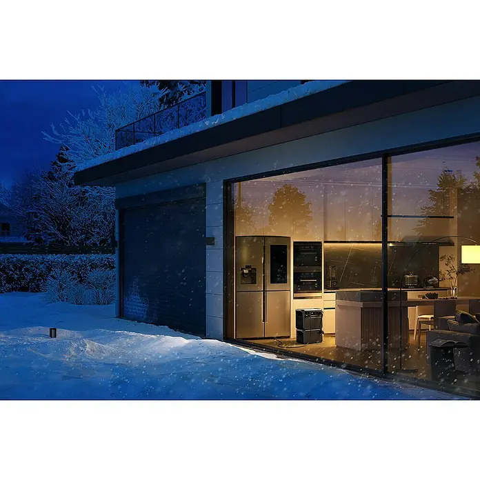 DJI Powerstation Power 2000 - 2.048 Wh, Schwarz - Stromspeicher im Winter vor einem Haus platziert, der das Haus bei Stromausfällen mit Energie versorgt und für Sicherheit sorgt.