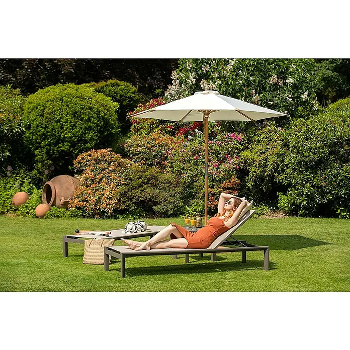 Kai Wiechmann Garten-Beistelltisch - Quadratisch, Taupe - Eine Frau entspannt auf einer Sonnenliege im Garten unter einem Sonnenschirm. Entspannung pur im eigenen Garten mit Gartenmöbel.