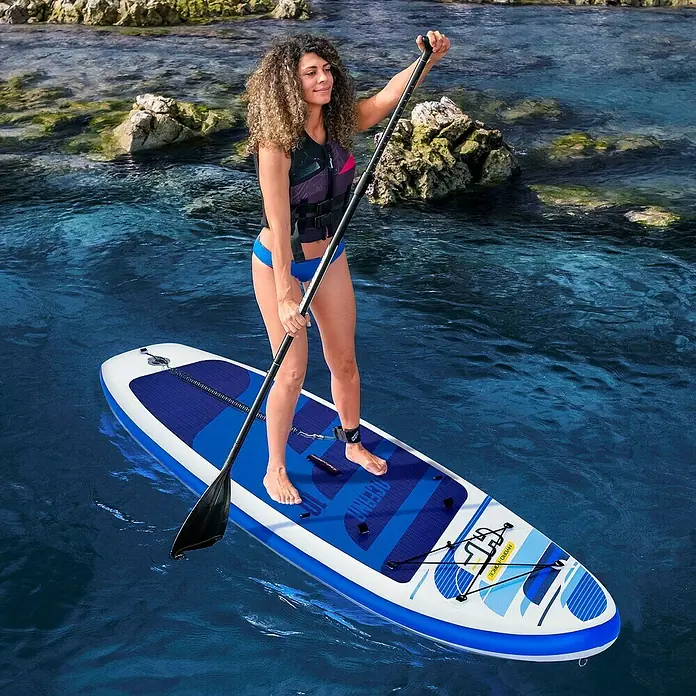 Bestway Juego de paddle surf Oceana - L x An x Al: 305 x 84 x 12 cm, Carga útil: 120 kg, Hinchable - Mujer de pie sobre una tabla de paddle surf inflable OceanWave en el agua, sujetando un remo.