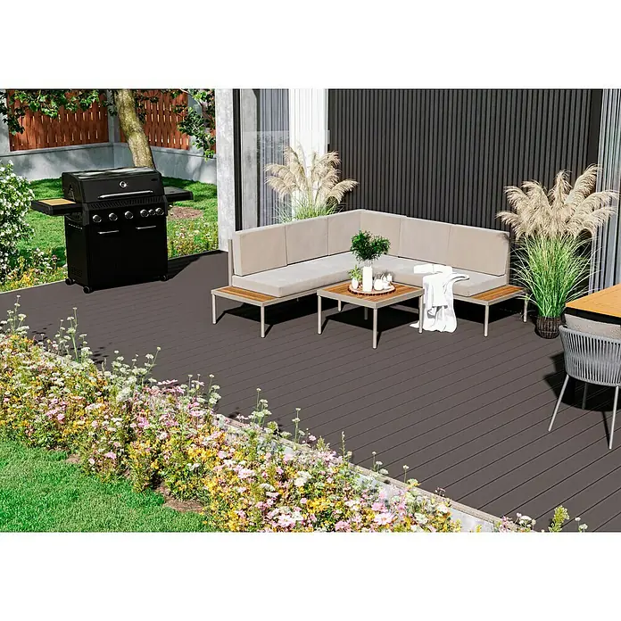 Kovalex WPC-Terrassendiele Exklusiv nach Maß - 300 x 14,5 x 2,6 cm, Grau - Elegante Gartengarnitur mit Grill, Sitzecke und Tisch auf einer Terrasse, umgeben von üppiger Blumenpracht. Ideal für entspannte Stunden im Freien.