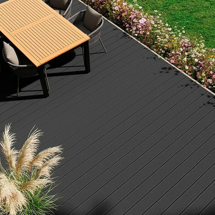 Kovalex WPC-Terrassendiele Exklusiv nach Maß - 600 x 14,5 x 2,6 cm, Steingrau - Hochwinkelaufnahme einer Terrasse aus grauen Dielen, die mit einem Tisch und Stühlen sowie dekorativen Pflanzen geschmückt ist.