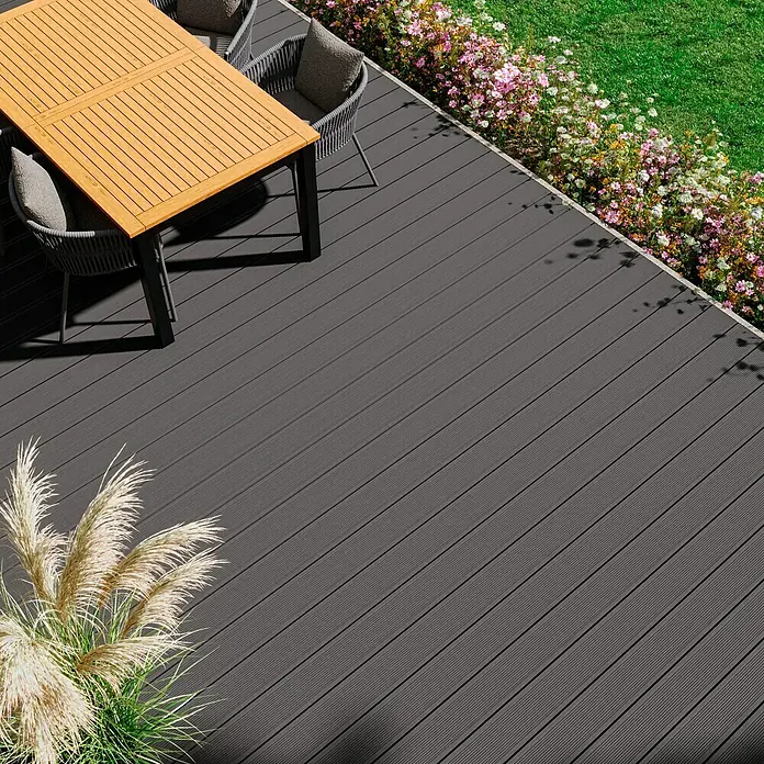 Kovalex WPC-Terrassendiele Exklusiv nach Maß - 300 x 14,5 x 2,6 cm, Grau - Hochwinkelaufnahme einer grauen Terrassendiele mit Gartenmöbeln und Blumen. Ideal für Außenbereiche und Gärten.