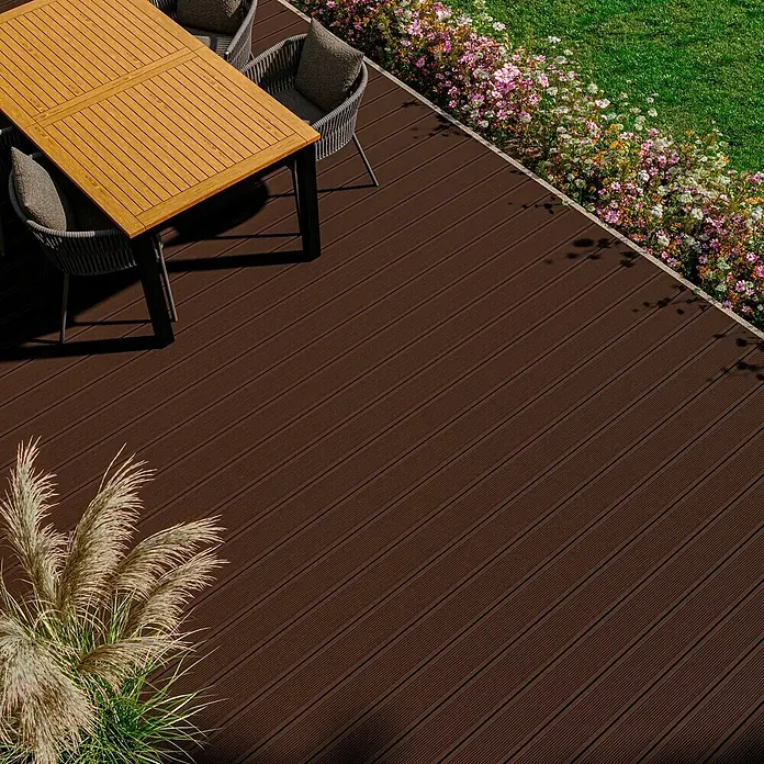 Kovalex WPC-Terrassendiele Exklusiv nach Maß - Braun, Gebürstet, 460 x 14,5 x 2,6 cm - Nahaufnahme eines braunen Terrassendielenbodens mit Gartenmöbeln und Bepflanzung. Die Oberfläche der Dielen ist durchgehend geriffelt.