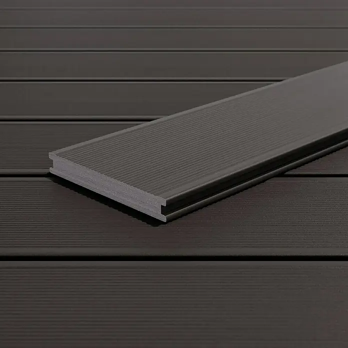 Kovalex WPC-Terrassendiele Massiv mit Struktur nach Maß - Graubraun, 310 x 14,5 x 2 cm - Nahaufnahme einer dunkelbraunen Terrassendiele mit geriffelter Oberfläche, die auf weiteren Dielen desselben Materials liegt.