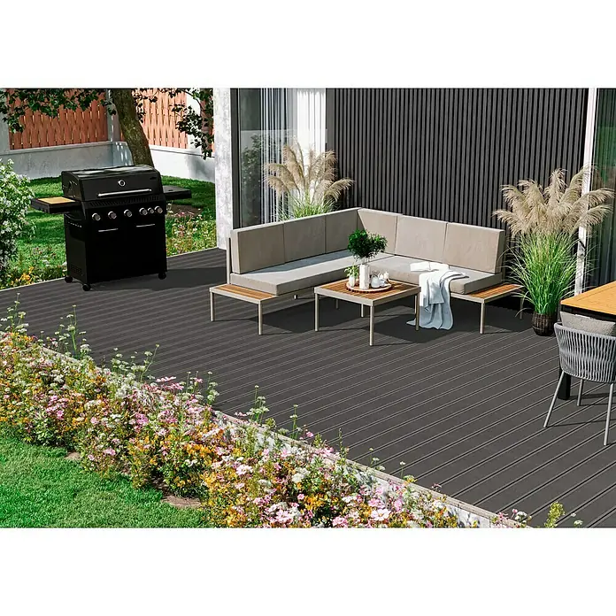 Kovalex WPC-Terrassendiele Exklusiv nach Maß - Grau, Gebürstet, 320 x 14,5 x 2,6 cm - Eine stilvolle Außenterrasse mit grauen Dielen, einer grauen Lounge, einem Grill und Blumenbeeten im Garten.