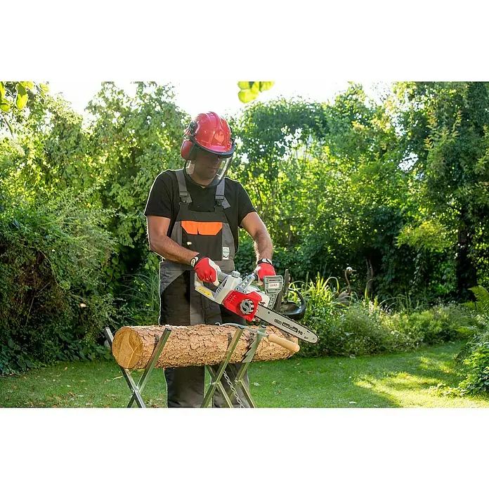 Ikra Akku-Kettensäge ICC 2/2035 - 40 V, 2 Ah, Li-Ionen, 2 Akkus - Ein Mann mit Schutzkleidung sägt mit einer IKRA Elektro-Kettensäge ein Holzscheit auf einem Sägebock im Garten.