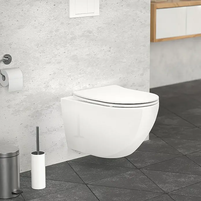 LuxeBath Wand-WC Hochwertiges Weiß mit Antibakterieller Oberfläche Duroplast - Spülrandlos, Spülform: Tief, WC Abgang: Waagerecht, Weiß - Weisse, wandhängende Toilette mit weissem Deckel vor einer grauen Wand und dunklen Bodenfliesen, mit Toilettenpapierhalter und Mülleimer.