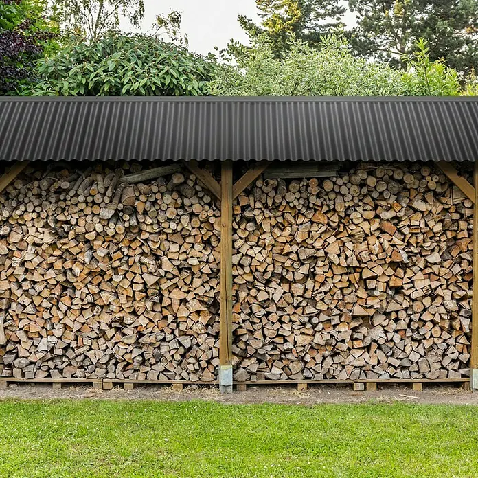 Wellplatte - 1.200 x 900 x 0,9 mm, Polycarbonat, Schwarz, Glatt, 76/18 mm, Rund - Holzschuppen voller Brennholz unter einem gewellten Blechdach, ideal zum Trocknen und Lagern von Holz für den Winter.
