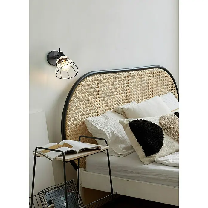 Trio Lighting Aplique de pared - 10 W, L x An x Al: 14 x 14 x 27,5 cm, Negro, E27 - Primer plano de una cama con una mesita de noche, una lámpara y almohadas decorativas, que muestra un ambiente de dormitorio acogedor y elegante.
