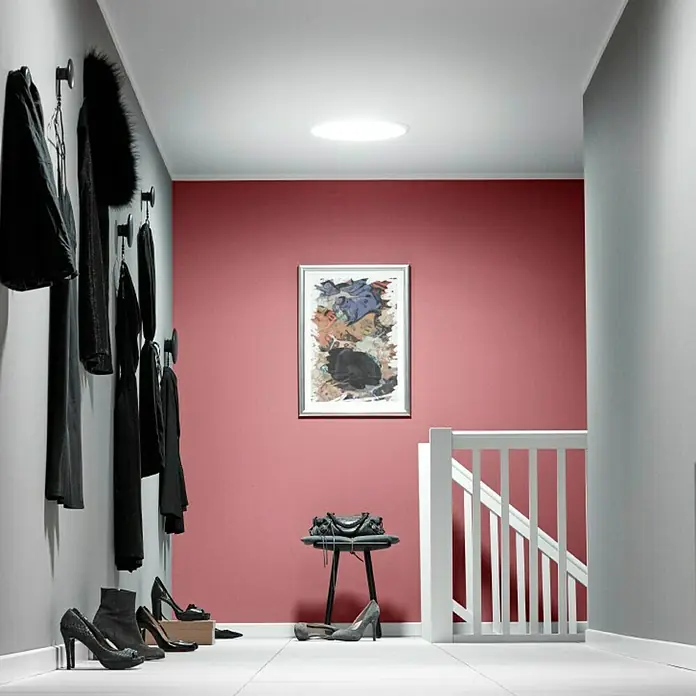 Velux Tageslicht-Spot TWR OK14 SDOW1 - Dachneigung: 15 ° - 60 ° - Ein stilvoller Flur mit Tageslicht durch ein Dachfenster, Garderobe und Kunstwerk an einer farbigen Wand.