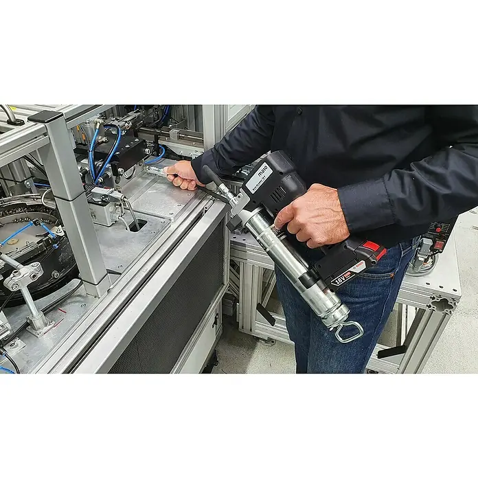 Mato Akku-Fettpresse Basic-S-LSP - 18 V, Ohne Akku, Max. Druck: 700 bar - Ein Mann benutzt eine Mato Akku-Fettpresse 18V, um eine Maschine zu warten, mit Fokus auf das Werkzeug und seine Anwendung im industriellen Kontext.