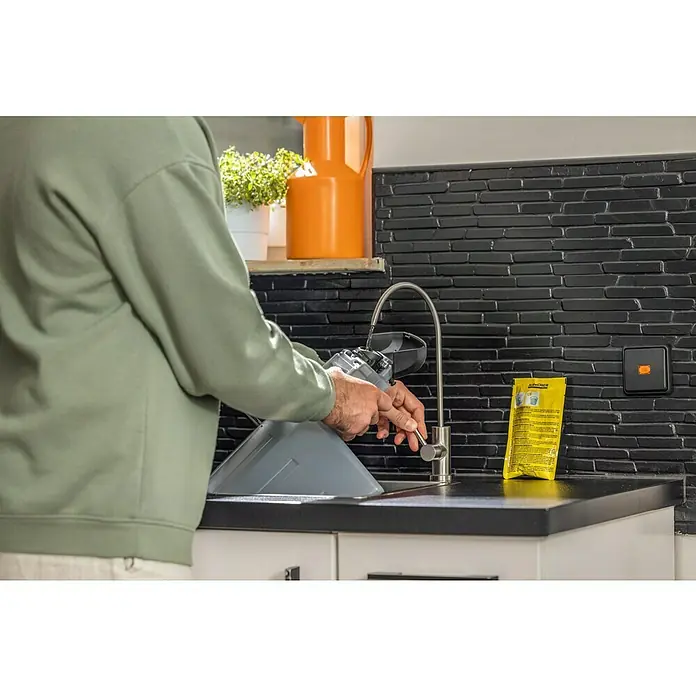 Kärcher Waschsauger SE 4004 - 1.000 W, Behältervolumen: 4 l - Ein Mann befüllt einen Kärcher Fenstersauger mit Wasser am Waschbecken, neben ihm liegt ein Reinigungsmittel.