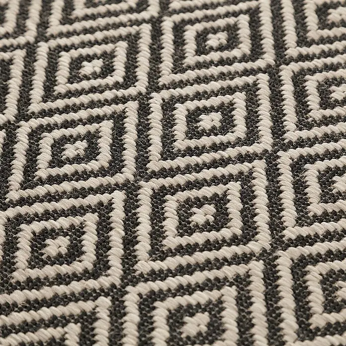 Dekoria Flachgewebeteppich - schwarz, beige, 230 x 160 cm - Nahaufnahme eines Teppichs mit geometrischem Rautenmuster in Schwarz und Beige, der eine interessante Textur und Tiefe zeigt.