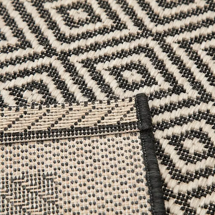 Dekoria Flachgewebeteppich - schwarz, beige, 230 x 160 cm - Nahaufnahme eines gewebten Teppichs mit geometrischem Diamantmuster in Schwarz und Beige, der seine Textur und Verarbeitung hervorhebt.