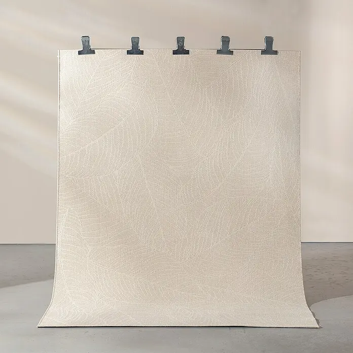 Dekoria Flachgewebeteppich - creme, beige, 230 x 160 cm - Nahaufnahme eines hellen Teppichs mit Blattmuster, der mit Klammern an einer Wand befestigt ist und auf einem grauen Boden liegt.