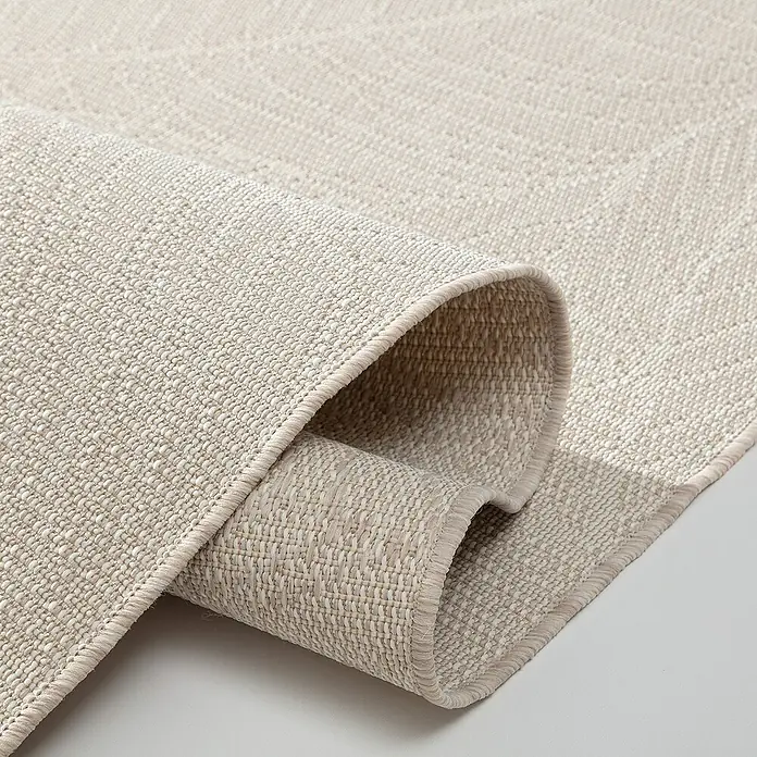 Dekoria Flachgewebeteppich - creme, beige, 230 x 160 cm - Nahaufnahme eines hellen, gewebten Teppichs, der aufgerollt ist und die Textur und das Material des Teppichs hervorhebt.