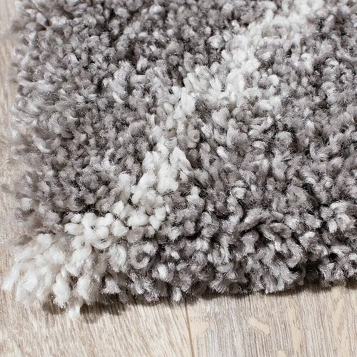 Dekoria Flachgewebeteppich - grau, 170 x 120 cm - Nahaufnahme eines grauen und weißen Shaggy-Teppichs auf einem hellen Holzboden.