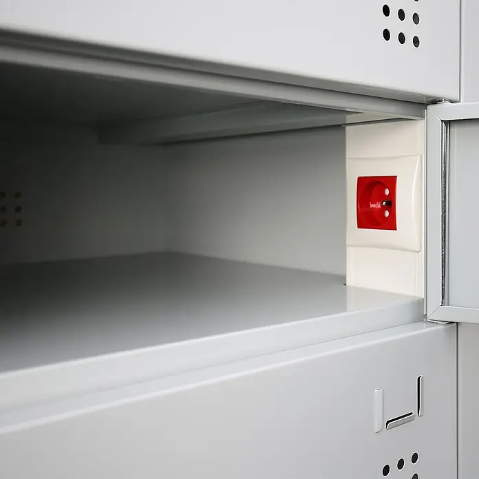 Lüllmann Laptopschrank - H x B x T: 180 x 50 x 50 cm, Lichtgrau/Enzianblau, Fertig montiert, Mit Steckdose, Anzahl Fächer: 10 Stk. - Innenansicht eines grauen Metallschließfachs mit einer roten Steckdose an der Seitenwand für elektronische Geräte.