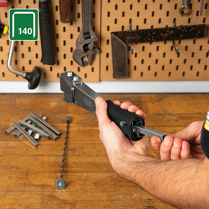 Rapid Hammertacker R11 - Klammertiefe: 6 mm - 10 mm, Geeignet für: Flachdrahtklammern Nr. 140 - Nahaufnahme einer Person, die einen silbernen Klammeraffe mit einem schwarzen Griff hält, auf einem Holztisch.