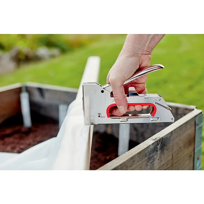 Rapid Handtacker R153 - Klammertiefe: 4 mm - 8 mm, Geeignet für: Klammern Typ 53 - Eine Hand befestigt eine weiße Folie mit einem Rapid-Tacker an einem Holzkasten, ideal für Gartenprojekte und DIY-Anwendungen.