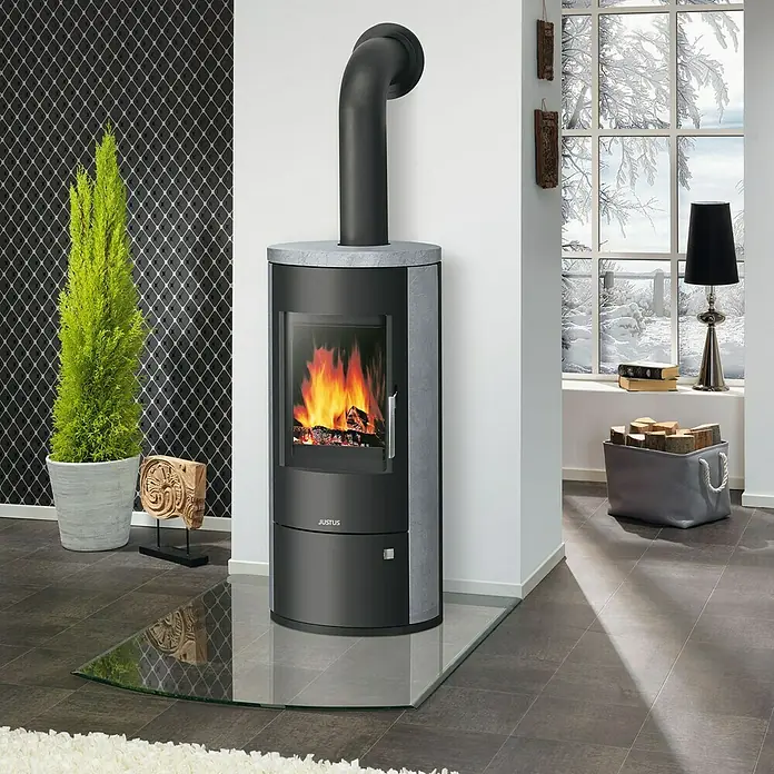 Justus Kaminofen Austin 7 - 7 kW, Raumheizvermögen: 144 m³, Material Verkleidung: Speckstein, Schwarz/Speckstein - Das Bild zeigt einen Justus Kaminofen mit Glasbodenplatte, der Wärme und Stil in jeden Raum bringt.