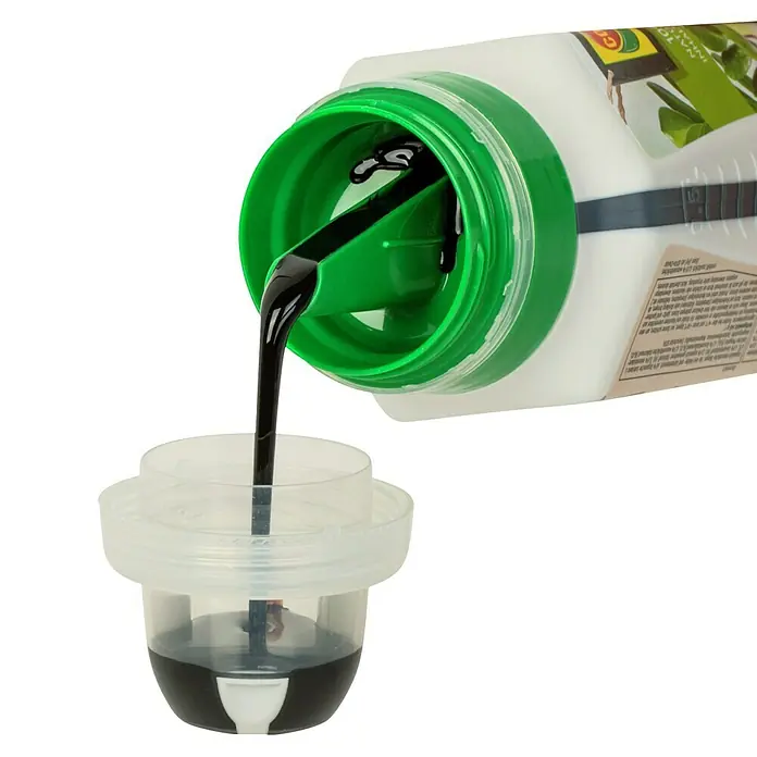 Compo Bio Grünpflanzendünger - 500 ml - Flüssigkeit wird in einen Messbecher aus einer Flasche mit grünem Deckel gegossen.
