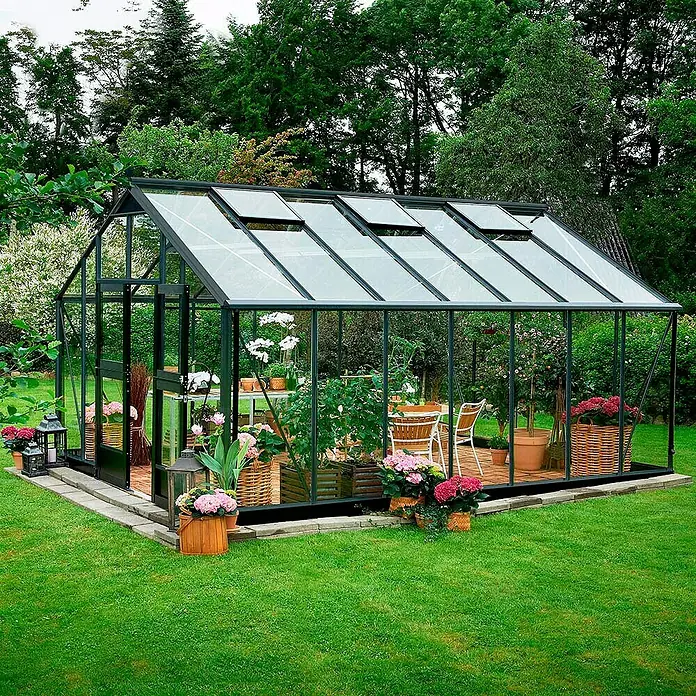 Juliana Gewächshaus Gärtner - Außenmaß inkl. Dachüberstand (B x T): 368 x 511 cm, Material Seitenwand: Glas, 3 mm, Anthrazit/Schwarz - Geräumiges Gewächshaus mit Pflanzen und Blumen. Die Konstruktion hat Fenster im Dach und eine Tür an der Seite.