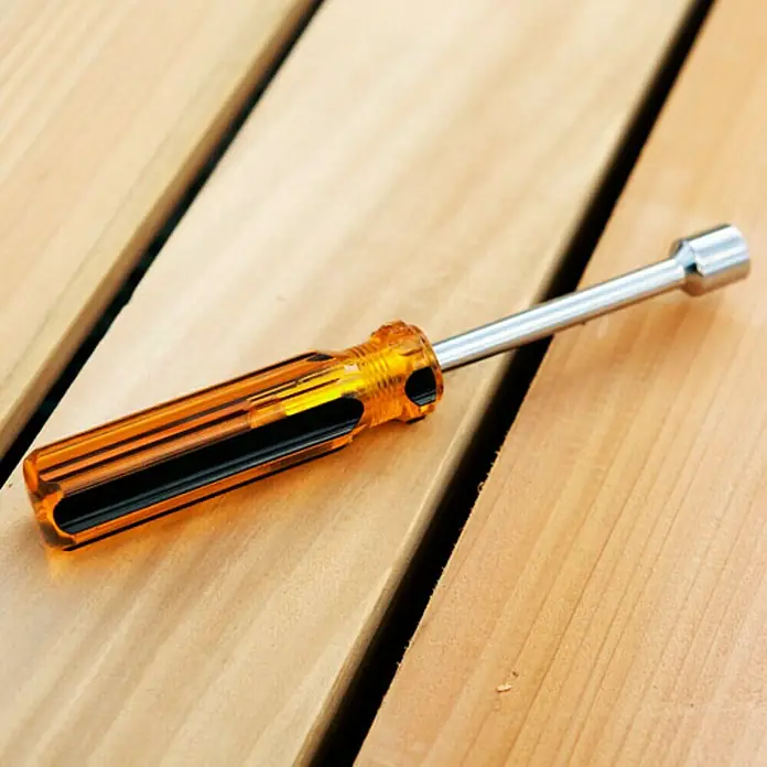 Juliana Schraubenschlüssel - Passend für: Juliana Gewächshäuser, Länge: 7 cm - Nahaufnahme eines orangefarbenen Schraubendrehers mit Stecknuss auf einem Holztisch. Ein nützliches Werkzeug für Heimwerkerprojekte und Reparaturen.