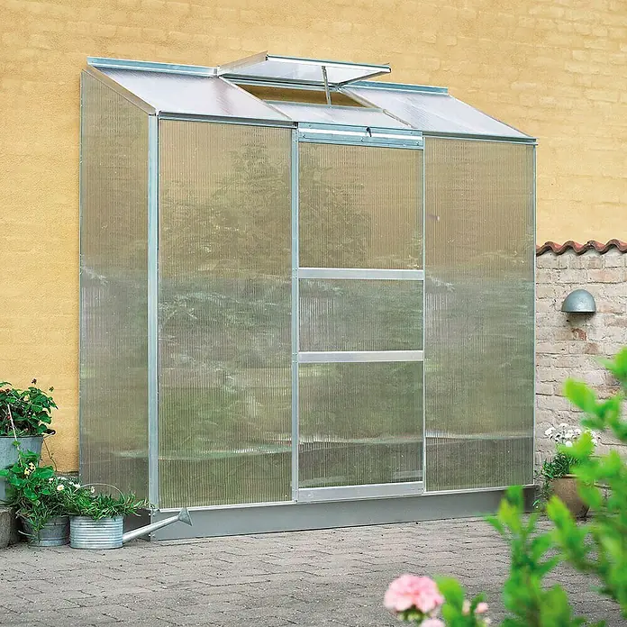 Halls Gewächshaus Altan 3 - Außenmaß inkl. Dachüberstand (B x T): 193 x 68 cm, Material Seitenwand: Kunststoff, 4 mm, Silbergrau - Gewächshaus an gelber Wand mit Pflanzen und Blumen. Das Gewächshaus bietet ausreichend Platz für das Pflanzenwachstum.