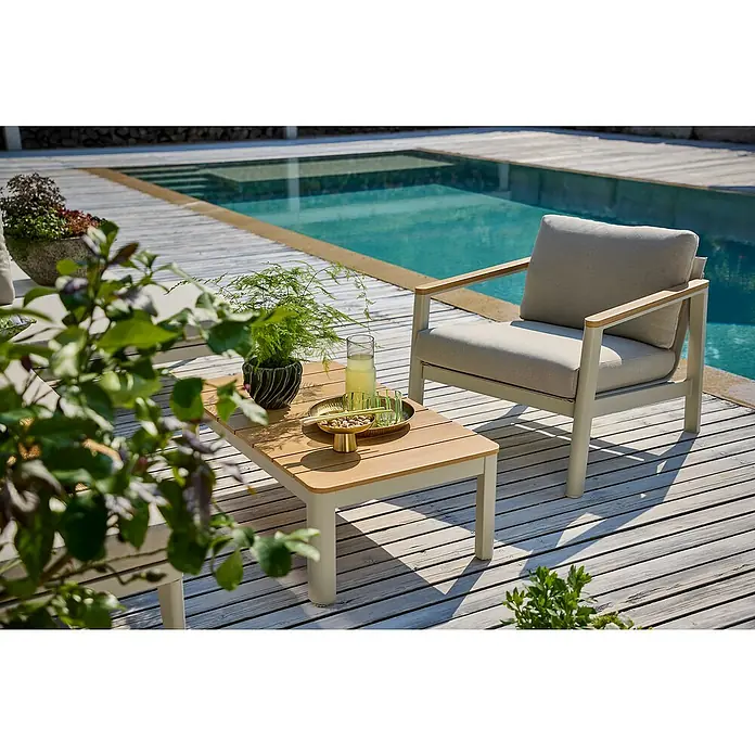 Sunfun Solo Loungetisch - B x T x H: 99,5 x 57 x 32,5 cm, Aluminium, Light-Greige - Blick auf einen Terrassenbereich mit stilvollem Loungesessel, Beistelltisch mit Getränken und Pflanzen am Pool.