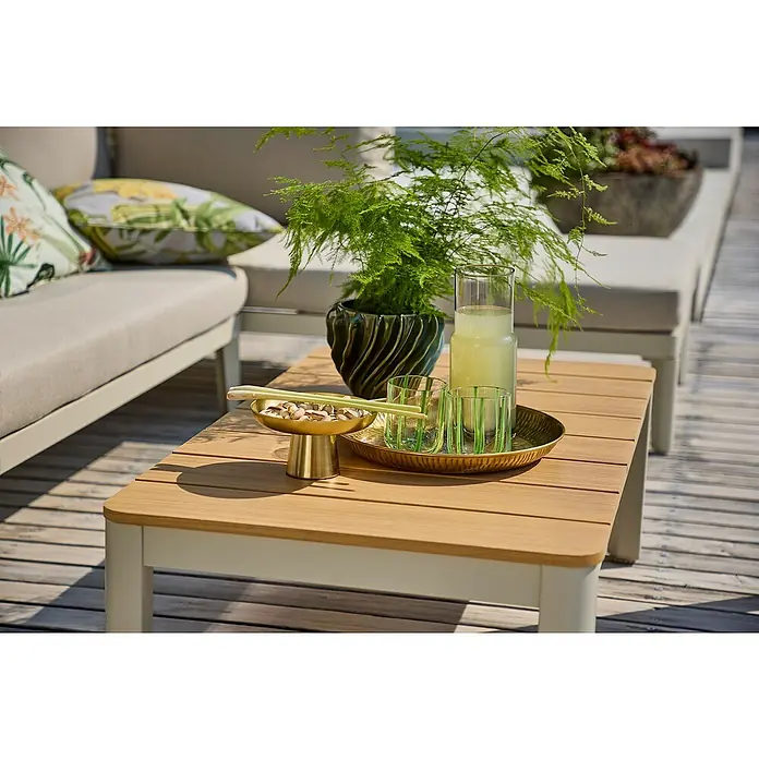 Sunfun Solo Loungetisch - B x T x H: 99,5 x 57 x 32,5 cm, Aluminium, Light-Greige - Nahaufnahme eines quadratischen Tisches aus Holz mit Pflanzen, Getränken und Snacks, der eine entspannte Gartenszene zeigt.