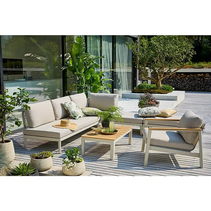Madison Outdoor-Kissen - 50 x 50 cm, Diez, Baumwoll-Polyester-Mischgewebe - Einladende Gartenmöbel-Anordnung auf einer Holzterrasse mit einem Sofa, Sessel und einem Couchtisch, umgeben von üppigem Grün.