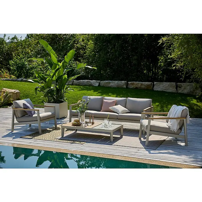 Sunfun Solo Loungemöbel-Set - 4 -tlg., Aluminium, Olefin, Loungetisch, Light-Greige - Elegante Gartenmöbel-Loungegruppe mit Sofa, Sesseln und Tisch auf einer Holzterrasse am Pool, umgeben von üppigem Grün.