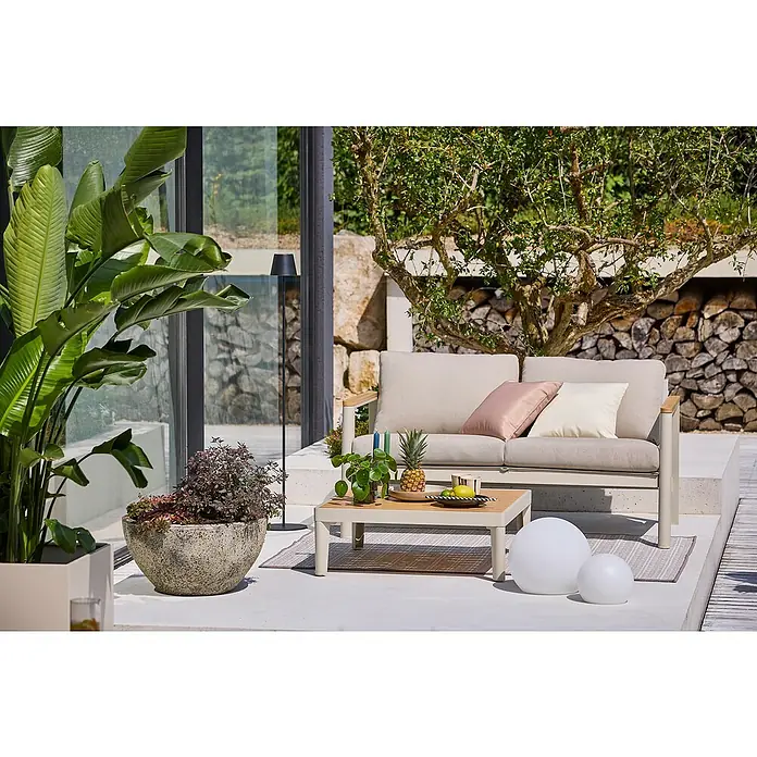 Sunfun Solo Loungemöbel-Set - 2 -tlg., Aluminium, Olefin, Light-Greige - Outdoor-Szene mit beigem Sofa, Tisch mit Ananas und Kugellampen auf einer Terrasse. Einladende Gartengestaltung mit stilvollen Möbeln.