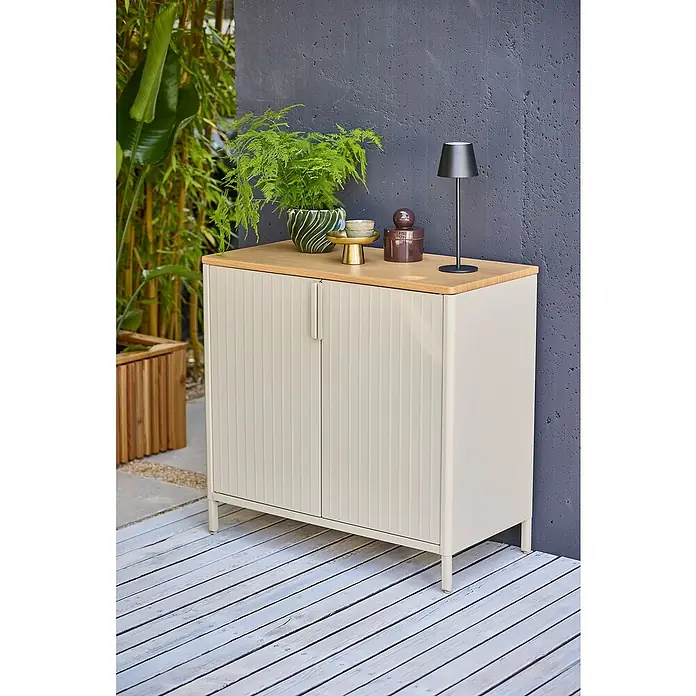 Sunfun Solo Garten-Aufbewahrungschrank - L x B x H: 90 x 46 x 86 cm, Stahl, Polywood, Light-Greige - Elegantes Sideboard mit Holzplatte und geriffelten Türen, ideal für den Außenbereich. Darauf Dekorationen und eine Lampe.