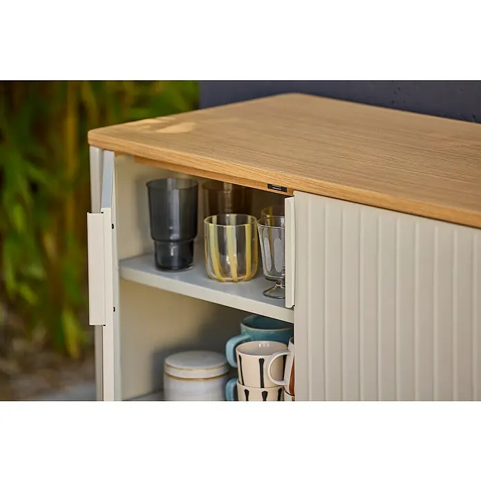 Sunfun Solo Garten-Aufbewahrungschrank - L x B x H: 90 x 46 x 86 cm, Stahl, Polywood, Light-Greige - Detailaufnahme eines Sideboards mit Gläsern und Tassen. Das Sideboard hat eine helle Holzplatte und eine gerippte Schiebetür.