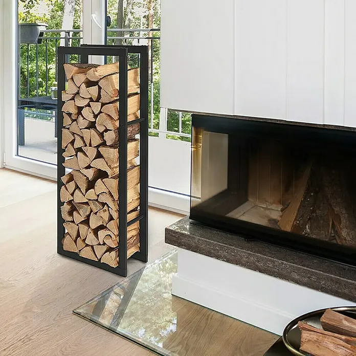 Floordirekt Kaminholzregal Kreta 100 x 25 x 100 cm - Metall, Schwarz - Ein moderner Kaminholzständer aus Metall, gefüllt mit Holz, steht neben einem Kamin in einem hellen Wohnzimmer.