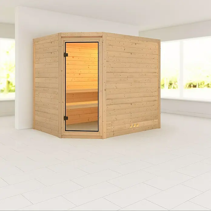 Karibu Massivholzsauna Tanami - Ohne Ofen, Ohne Dachkranz, L x B x H: 231 x 196 x 192 cm - Eine freistehende Sauna aus hellem Holz mit Glastür in einem hellen Raum. Die Sauna bietet Entspannung und Wellness für Zuhause.