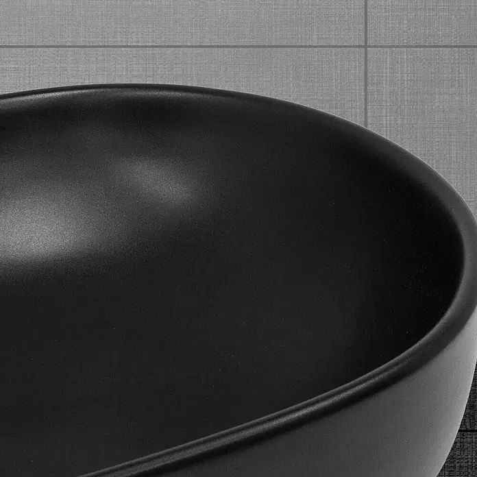 LuxeBath Aufsatzwaschbecken Handwaschbecken Schwarz inkl. Ablaufgarnitur ohne Überlauf - Ohne Spezialglasur, Schwarz - Nahaufnahme einer eleganten, schwarzen Waschschüssel mit glatter Oberfläche und modernem Design vor einem grauen Hintergrund.
