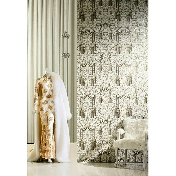 Glööckler Vliestapete - Beige/Silber, Streifen, 10,05 x 0,7 m - Elegantes Interieur mit einem goldenen Kleid auf einer Schneiderpuppe und einem weißen Sessel vor einer stilvollen Tapete.